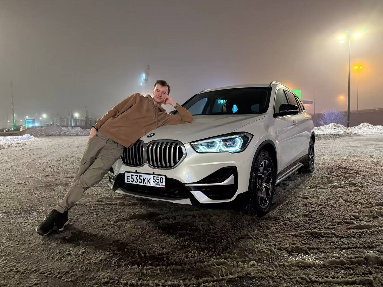 Покупатель рядом с полученным автомобилем BMW